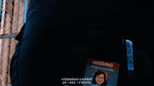 a person is standing in front of a chain link fence with a missing sign on their back