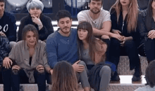 a group of people are sitting in a stadium watching a man and a woman hugging each other .