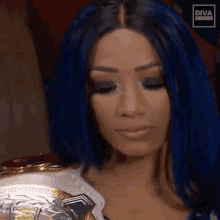 a woman with blue hair is holding a championship belt around her neck .