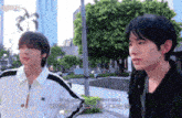 two young men are standing next to each other on a sidewalk in front of a building .