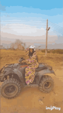 a woman wearing a helmet is riding an atv in the dirt
