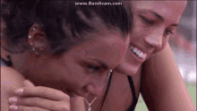 two women are hugging each other and smiling while one of them is crying .