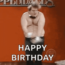 a man without a shirt is dancing in front of a red wall and saying happy birthday .
