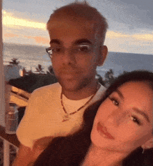 a man and a woman pose for a picture in front of the ocean