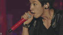 a man singing into a red microphone with the letter d visible