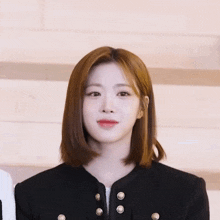 a woman wearing a black jacket with gold buttons on the sleeves