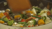 a pan filled with vegetables is being stirred with a wooden spoon