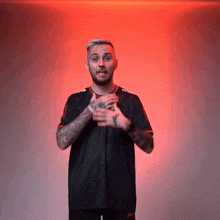 a man with a tattoo on his arm is standing in front of a red wall
