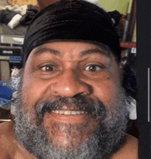 a man with a beard and a black headband smiles for the camera