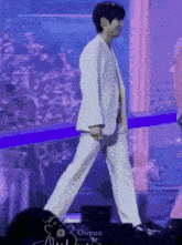 a man in a white suit is walking on stage