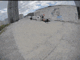 a drone is flying in front of a fence with graffiti on it that says " axx "