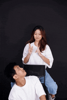 a woman in a white shirt is sitting on a chair and making a peace sign