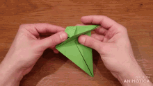 a person is holding a green origami object and the words made in animatica can be seen behind them