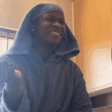 a man wearing a robe with a hood on his head is smiling .