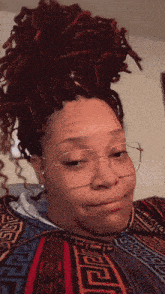 a woman with dreadlocks wearing glasses and a shirt with a greek key pattern