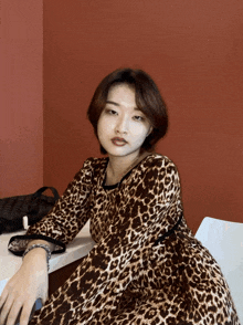 a woman in a leopard print dress sits on a chair