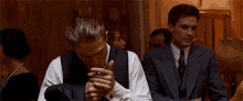 a man in a suit is smoking a cigarette in a room
