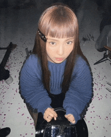 a girl in a blue sweater is kneeling down