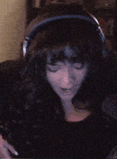 a woman wearing headphones and a black top looks to the side
