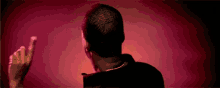 a man with a beard is standing in front of a red background and making a funny face .