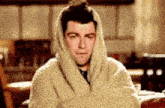 a man is wrapped in a blanket with his arms crossed .