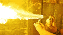 a person is holding a spray can with flames coming out of it
