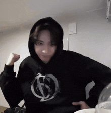 a person wearing a black hoodie with a white circle on the front