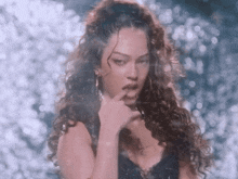 a woman with curly hair has her finger to her lips