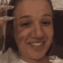 a woman with a nose ring is sitting on a couch drinking a drink with a straw .