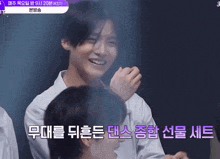 a man in a white shirt is smiling in front of a sign that says ' kst ' on it