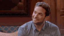 a man with a beard is smiling while sitting on a couch