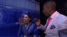 a man in a suit and tie is standing next to a woman in a blue dress