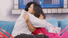 a man and woman are hugging each other while sitting on a couch .