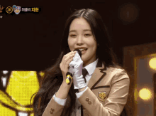a girl in a school uniform is singing into a microphone with the number 2r in the corner
