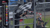 a man waving a checkered flag behind a fence with a finish sign above him