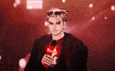 a man in a red and black outfit is holding a red object