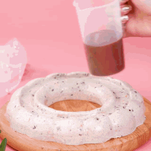 chocolate is being poured on a doughnut on a wooden cutting board