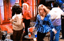 a woman in a blue shirt is standing in a crowd of people dancing