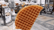 a waffle is being held up in front of a sign that says made in animotica