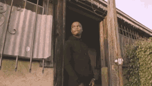 a man in a black hoodie is standing in the doorway of a building ..