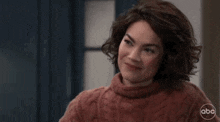 a woman in a red sweater is smiling and looking to the side .