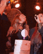 a woman stands in front of a cake with a happy birthday sign on it