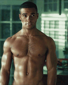 a shirtless man is standing in front of a window and smiling