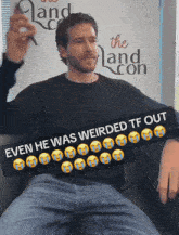 a man is sitting in front of a sign that says " the land con "