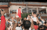 a man in a red scarf stands in a crowd of people