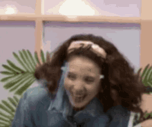 a woman wearing sunglasses and a headband is laughing while sitting in front of a window .