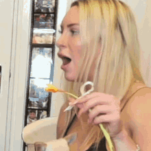 a woman eating something with a spoon in front of a wall of pictures