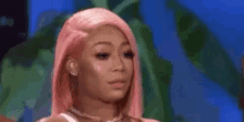 a woman with pink hair is looking at the camera .