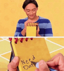 a man is holding a yellow notebook that says need dat on it