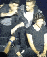 a man in a black shirt is sitting next to another man in a black shirt